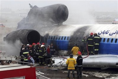 Iranian firefighters work on a burned Russian-made Iranian passenger plane after its crash landing at Mashhad airport, northeastern Iran, Sunday, Jan. 24, 2010.
