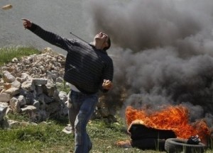 palestinian youth throws stone at israelis
