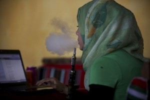 A Palestinian woman smokes a water pipe as she checks the Internet at a cafe in Gaza City
