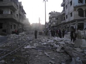 Residents stand among the ruins of buildings destroyed in what activists said was an air strike by the Syrian Air Force at al-Khalidiah neighborhood in Homs