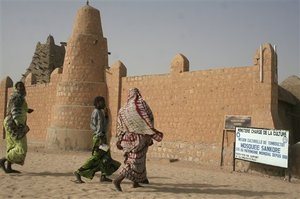 AP Photo - People dressed in colorful dress walk near the Sankore Mosque, a United Nations world heritage cultural site, which would not be allowed under the rule of Islamic militants who ruled the city until French troops took control, in Timbuktu, Mali, Thursday Jan. 31, 2013. Many things have changed in Timbuktu since French troops parachuted in several days ago to take control of the area from Islamic militants, and now there is a growing sense of freedom.