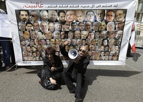 Lebanese protesters shout slogans in front of a banner with portraits of the 128 Lebanese lawmakers with Arabic that reads, "you failed in everything, failed, failed, failed, go home," during a protest against a 17-month extension of the terms of the Lebanese parliament, near the parliament building in Beirut, Lebanon, Friday May 31, 2013. The extension of the 128-seat legislature's term marks the first time that parliament has had to extend its term since Lebanon's own 15-year civil war ended in 1990, and underlines the growing turmoil as a result of the Syrian conflict. (AP Photo/Hussein Malla)