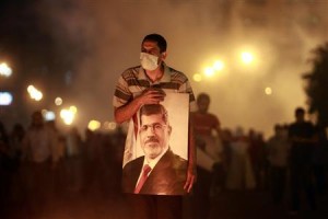 File photo of an injured supporter of deposed Egyptian President Mohamed Mursi carrying a poster of Mursi as they run from tear gas fired by riot police during clashes on the Sixth of October Bridge over the Ramsis square area in central Cairo