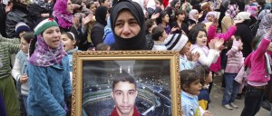 A demonstrator holds a picture of a missing relative during a protest against Syria's President Assad in Baba Amro
