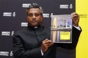 Amnesty International Secretary General Salil Shetty holds up a report during a news conference in Doha