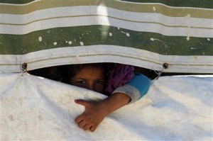 A Palestinian refugee girl from Syria peeps through a tent at Ain al-Helweh Palestinian refugee camp near the port-city of Sidon, southern Lebanon