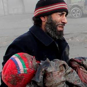 A syrian man cries while holding the body of a child who was killed in an a  Syrian government airstrike in Aleppo 