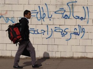 A student of Al-Azhar University walks along a wall covered with graffiti near a bus damaged by a bomb blast around the Al-Azhar University campus in Cairo's Nasr City district