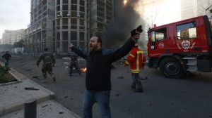 A security personnel shouts as smoke rises from the site of an explosion in Beirut's downtown area