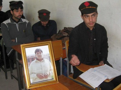 Pakistani students sit next to a picture of classmate Aitzaz Hasan, who residents and police say died this week while trying to stop a suicide bomber who was targeting his school in a remote village in Hangu, Pakistan, Friday, Jan. 10, 2014. Police said a teacher at the school told investigators that he saw Hasan chasing the attacker and then saw the attacker detonate the bomb that killed the teen. Local resident Miqdar Khan said people in the violence-prone district were hailing the teen as a hero.