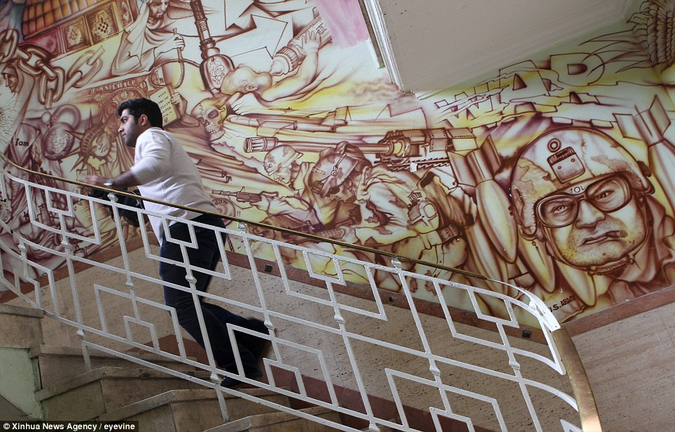 An Iranian Journalist climbs the stairs inside the former US embassy in downtown Tehran. Painted on the walls are anti-American murals