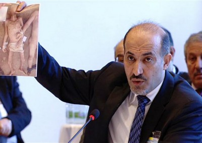 A TV grab made on January 22, 2014 from a United Nation's UNTV broadcast, shows Ahmed al-Jarba, the head of the Western-backed Syrian National Coalition, holding up an image of alleged opposition torture victims, during the Syrian peace talks in Montreux, Switzerland, Wednesday January 22, 2014. (Photo: AFP / UNTV)