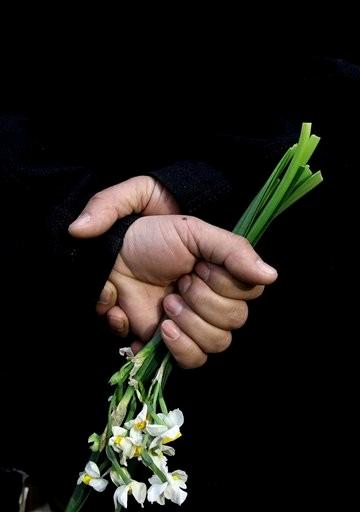 An Afghan member of a civil society organization holds flowers outside of the La Taverna du Liban restaurant, during an anti terrorism demonstration in Kabul, Afghanistan, Sunday, Jan. 19, 2014. AP Photo/Massoud Hossaini). 