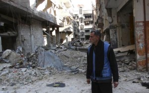 A man stands amid the rubble of damaged buildings at the Palestinian refugee camp of Yarmouk, south of Damascus