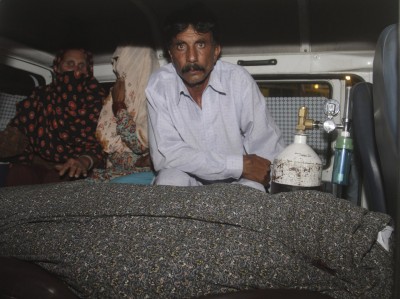 Mohammad Iqbal, right, husband of Farzana, sits in an ambulance next to the body of his pregnant wife who was stoned to death by her own family, in Lahore, Pakistan on Tuesday.