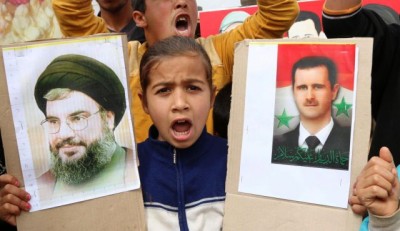 A Syrian refugee girl holds pictures of Syria's President Bashar Assad and Lebanon's Hezbollah leader Hassan Nasrallah, southern Lebanon, March 18, 2014. 
