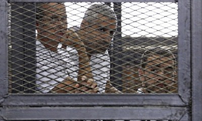 Al-Jazeera journalists Peter Greste, Mohamed Fahmy and Baher Mohamed behind bars at a court in Cairo