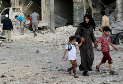 A woman with her children flee from a site hit by what activists said was a vacuum bomb dropped by forces loyal to Syria's President Bashar al-Assad, in the Tariq al-Bab neighbourhood of Aleppo June 8, 2014. REUTERS/Mahmoud Hebbo 