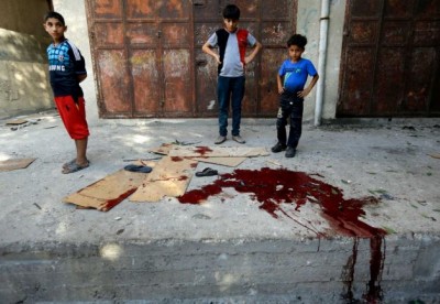 Palestinians look at a pool of blood from victims of an explosion that killed 10 people, 9 of them children, at a park at Shati refugee camp, in the northern Gaza Strip, Monday, July 28, 2014. Israeli and Palestinian authorities traded blame over the attack and fighting in the Gaza war raged on despite a major Muslim holiday. Photo: Lefteris Pitarakis, AP