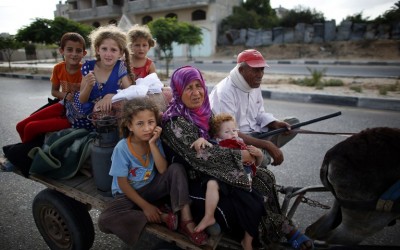 Palestinian families travel to a UN school in Gaza City to seek shelter after evacuating their homes in the northern strip, on Sunday, July 13, 2014 (photo credit: AFP/THOMAS COEX)