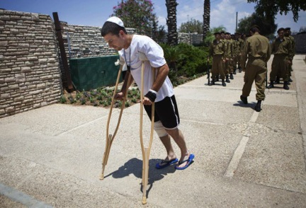 A wounded Israeli soldier arrives for the funeral of Maj. Tzafrir Bar-Or, 32, one of 13 soldiers killed in several separate incidents in Shijaiyah on Sunday, at the military cemetery in Holon, Israel, Monday, July 21, 2014.