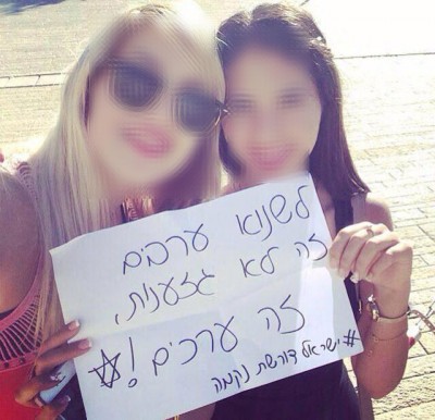 Two girls hold a sign that reads, 'Hating Arabs isn't racism, it's values. #IsraelDemandsRevenge'. 
