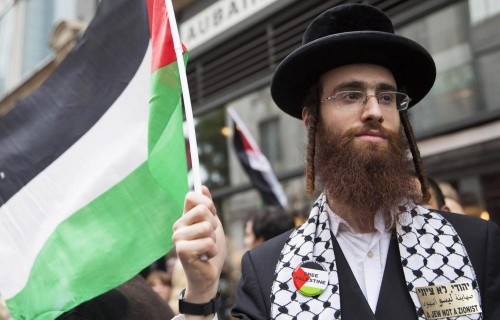 An American Jewish scholar holds a Palestinian flag during a protest against Israel's air strikes on Gaza.