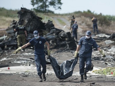 Emergency workers carry remains in a body bag as pro-Russia militants stand guard at the crash site of Malaysia Airlines Flight 17 near the Ukrainian village of Hrabove. (Photo: Evgeniy Maloletka, AP)