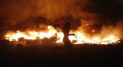 A Palestinian stone-thrower kicks a tyre set ablaze during clashes with Israeli police in the East Jerusalem neighbourhood of Wadi al-Joz during a protest against the Israeli offensive on Gaza July 25, 2014 