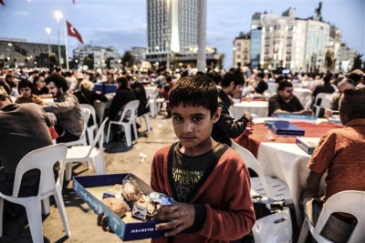 A Syrian boy stands with food he collected from tables after Turkish people break their fasting on July 4, 2014, at Taksim square during the holy month of Ramadan in Istanbul. AFP Photo