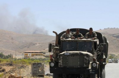 Lebanese army soldiers ride on a military pick-up truck at the entrance of the Sunni Muslim border town of Arsal, in eastern Bekaa Valley, as smoke rises in the background during clashes between Lebanese army soldiers and Islamist militants August 4, 2014.  REUTERS/Hassan Abdallah