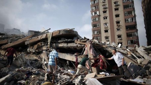 Palestinians collect items from the rubble of a 12-story apartment building that collapsed Saturday after it was hit in an Israeli airstrike in the heart of Gaza City. (Thomas Coex / AFP/Getty Images)