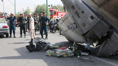 Iranian Revolutionary Guards and security forces stand next to the remains of a plane as they secure the scene of a crash near Tehran's Mehrabad airport on August 10, 2014. (AFP Photo / Atta Kenare)