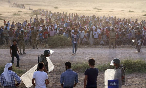 Turkish security forces stand guard as Syrians wait behind the border fences in Sanliurfa province. Turkey opened a stretch of the frontier yesterday after Kurdish civilians fled their homes, fearing an imminent attack on the border town of Ayn al-Arab, known as Kobani in Kurdish. – Reuters pic, September 20, 2014. -