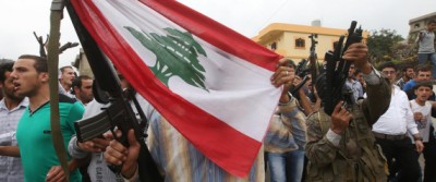 Lebanese Sunni gunmen hold their weapons and a Lebanese flag during the funeral procession of Sgt. Ali Sayid, who was beheaded by Islamic militants, in his home town of Fnaydek, in Akkar north Lebanon, on Wednesday, Sept. 3, 2014. Sgt. Ali Sayid went missing around the same time that some two dozen soldiers and police were seized by militants from Syria who overran the border town of Arsal for several days last month. The incursion was the most serious spillover yet of the Syrian civil war and escalated tensions in Lebanon, which is bitterly split over the conflict. (AP Photo/Hussein Malla)