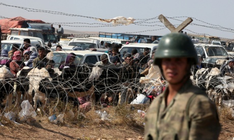 A Turkish soldier stands guard as Syrians from Kobani wait to enter Turkey at the border crossing of Yumurtalik on Thursday. Photograph: Burhan Ozbilici/AP