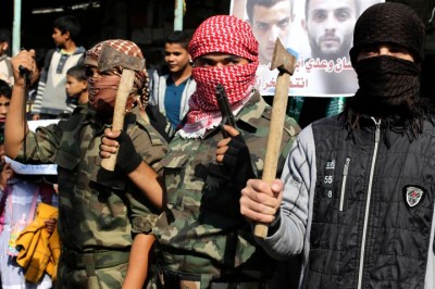 Masked Palestinians hold axes and a gun as they celebrate with others an attack on a Jerusalem synagogue, in Rafah in the southern Gaza Strip November 18, 2014.  