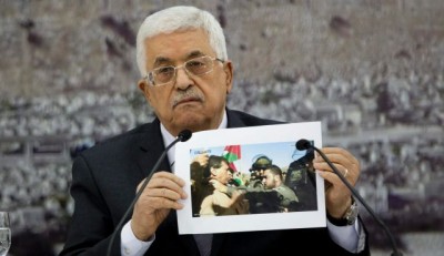 Palestinian President Mahmoud Abbas holds a picture of an Israeli soldier pushing Palestinian Cabinet minister Ziad Abu Ein, Ramallah, Dec. 10, 2014. Photo by AP