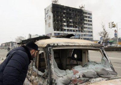A man looks into a burnt-out car near the Press House building, a local media agency, in Grozny, December 4, 2014. Reuters