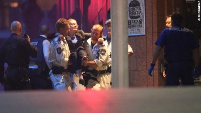 A injured hostage is carried to an ambulance after shots were fired during  a cafe  siege at Martin Place in the central business district of Sydney, Australia, Tuesday, Dec. 16, 2014. New South Wales state police would not say what was happening inside the cafe or whether hostages were being held. But television footage shot through the cafe's windows showed several people with their arms in the air.(AP Photo/Rob Griffith)