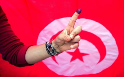 A Tunisian woman shows her ink stained finger after voting at a polling station