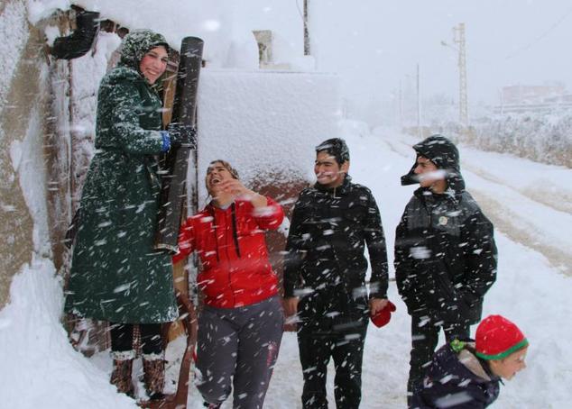 Syrian refugees stand amidst a snow storm at an unofficial camp on the road between Riyaq and Baalbek in Lebanon's eastern Bekaa Valley, near the border with Syria, on January 7, 2015