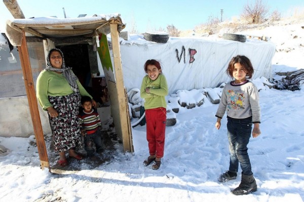 Syrian refugees pose in the snow in front of their makeshift home in Ankara. Adem Altan/AFP/Getty Images