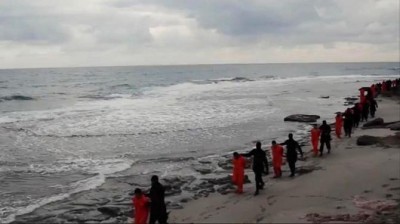 This image made from a video released militants in Libya claiming loyalty to the Islamic State group purportedly shows Egyptian Coptic Christians in orange jumpsuits being led along a beach, each accompanied by a masked militant. (Via AP)