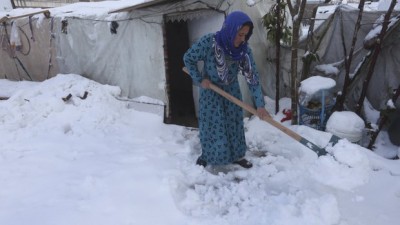 A Syrian woman removes snow from around her tent at a refugee camp in al-Majdal village, Bekaa valley, east Lebanon. 
