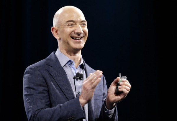 Amazon CEO Jeff Bezos holds a slide show controller and applauds at the start of the launch event for the new Amazon Fire Phone, Wednesday, June 18, 2014, in Seattle. (AP Photo/Ted S. Warren) ORG XMIT: WATW115