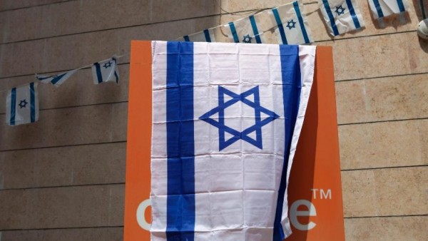 The Orange company logo is seen covered with an Israeli flag at the "Partner Orange" Communications Company's offices in the city of Rosh Haain, Israel, Thursday, June 4, 2015. An Israeli Cabinet minister has called on the French president to fire the chief executive of French telecom giant Orange. Culture Minister Miri Regev issued her appeal on Thursday, a day after Orange's CEO announced in Cairo that he would like to sever his company's ties to Israel as soon as possible. (AP Photo/Dan Balilty) 