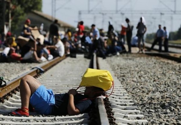 A migrant holds a sack pack on his head as he lies on the railway track in Tovarnik, Croatia September 17, 2015. REUTERS/Antonio Bronic