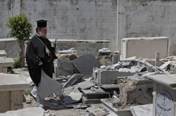 Greek Orthodox Archbishop of Gaza Alexios, walks past destroyed graves, hit by an Israeli strike, at the cemetery of the St. Porphyrios church in Gaza City, Sunday, Aug. 10, 2014. There are approximately 2,500 Christians among an overall Palestinian population of more than 1.7 million in Gaza. (AP Photo/Lefteris Pitarakis) ORG XMIT: XLP305