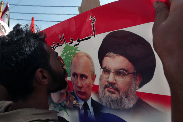 A Syrian who lives in Lebanon kisses a poster with photos of Russian President Vladimir Putin and Hezbollah leader   Hassan Nasrallah during a rally in front of the Russian embassy in Beirut 